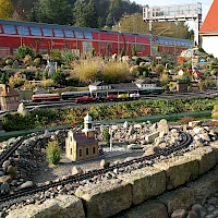 Nachbildung des Bahnhofs Pirna im Hintergrund: die echte Elbtalbahn(© KilianPaulUlrich; Wikipedia; CC BY-SA 3.0)
